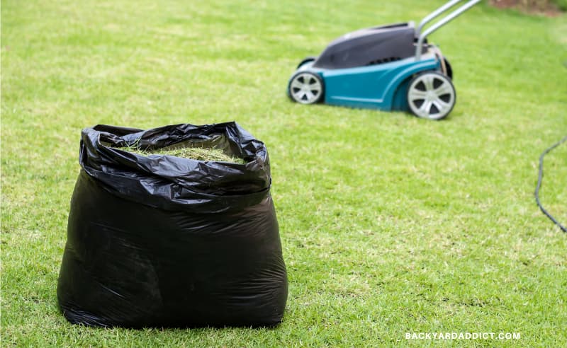 bag of lawn clippings with mulching lawn mower in the background