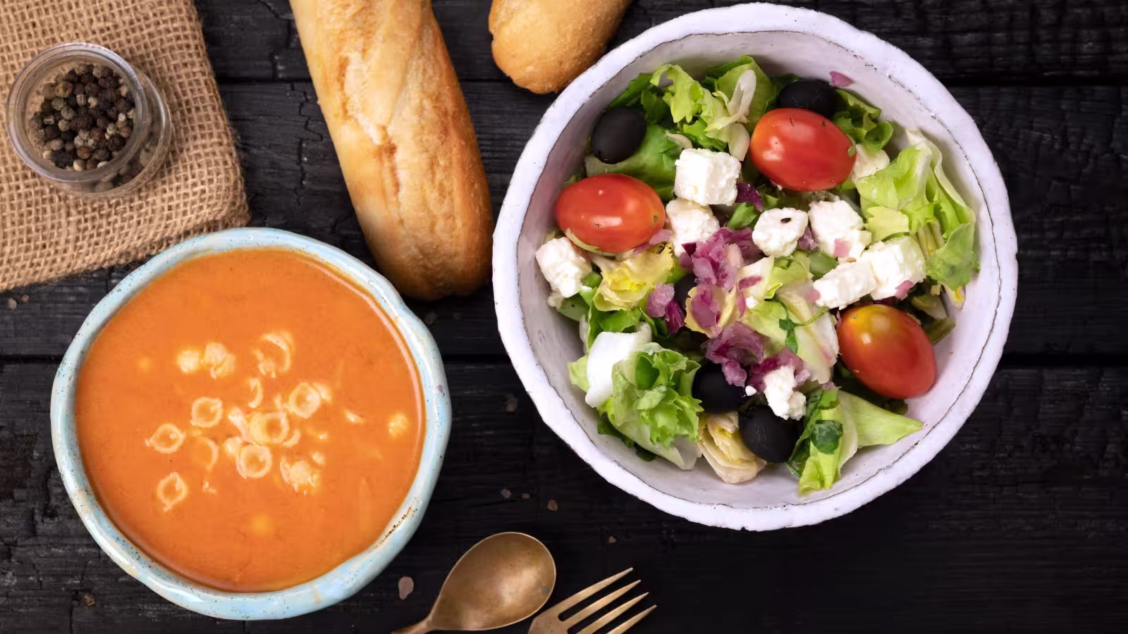 bowl of vegetable soup next to a bowl of salad with some bread