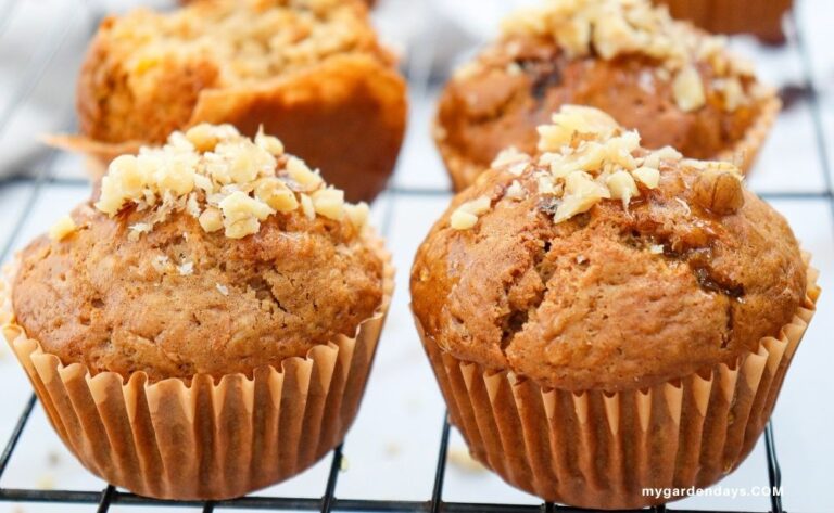 Close-up of golden brown carrot muffins topped with chopped walnuts cooling on a wire rack
