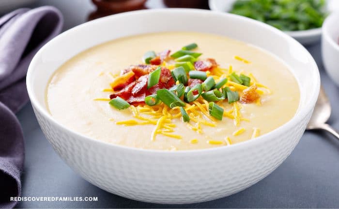 Bowl of creamy potato soup topped with bacon, cheddar cheese, and green onions