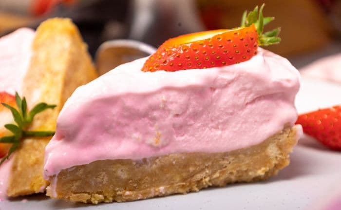 A slice of strawberry cheesecake with sliced strawberry